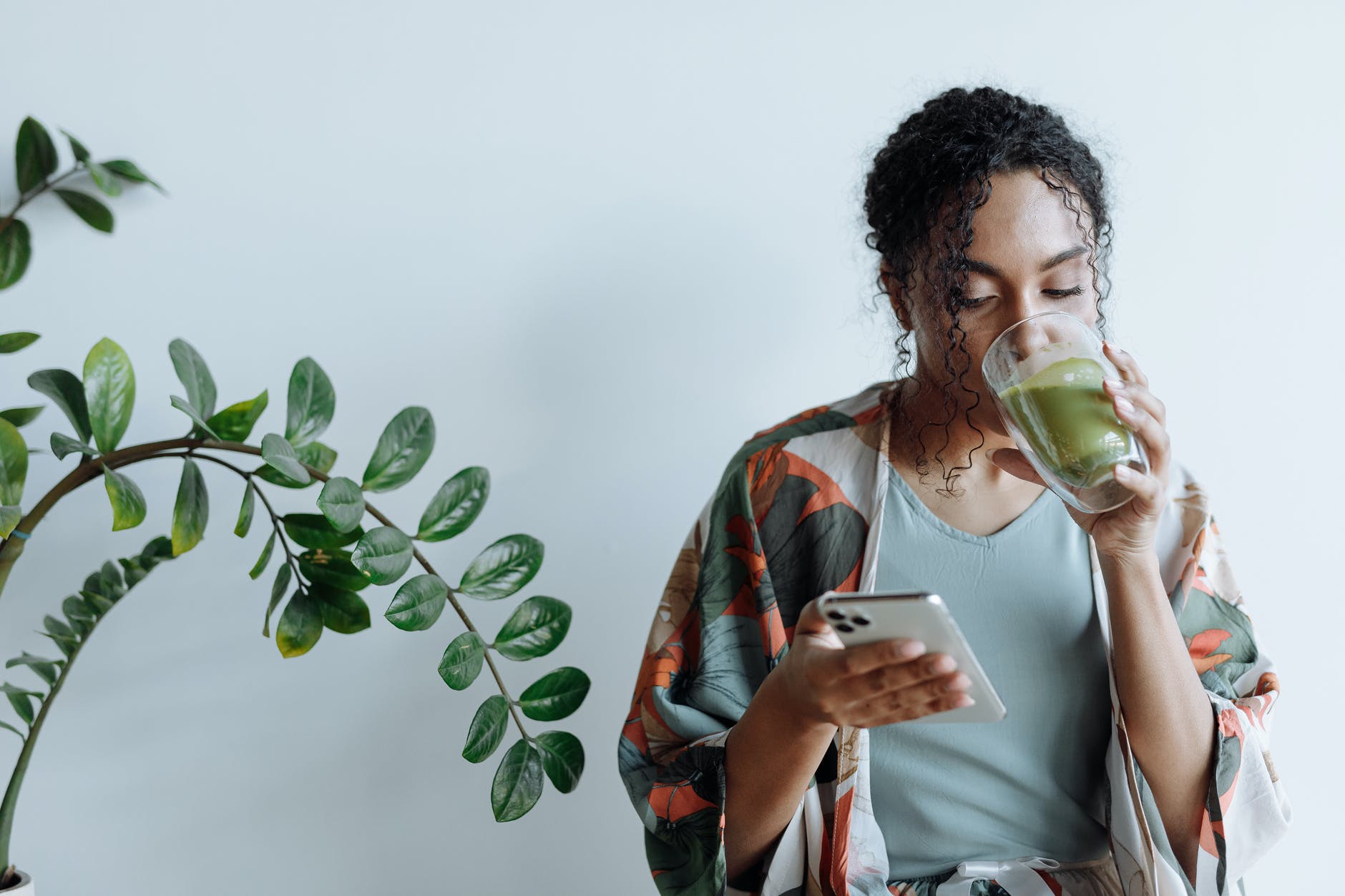 a woman drinking matcha while using her mobile phone